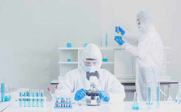 Два азиатских учёных резервируют химические трубки для экспериментов с биотехнологическими антителами в лаборатории Культивировать вакцину против вируса ковида-19. Ученые консультируют, анализируют в химической лаборатории - Фото, изображение