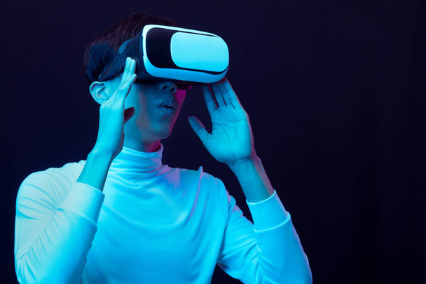 Jeune homme asiatique excité portant casque VR dans la lumière au néon, Concept de technologie future. - Photo, image
