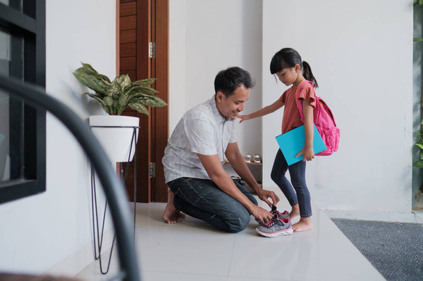 father helping his daughter wearing shoes before going to school - 写真・画像