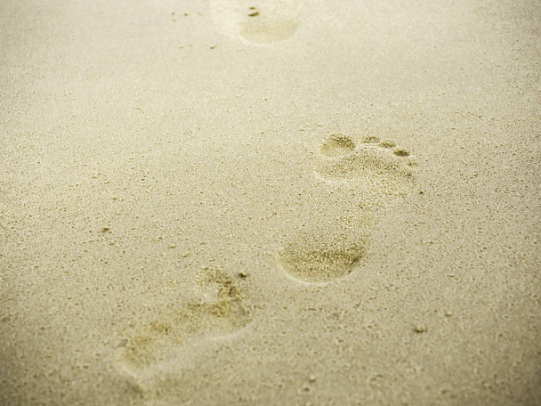 Παραλία άμμο πατημασιές με αντίγραφο χώρο. Κλείστε το ανθρώπινο αποτύπωμα από το περπάτημα ξυπόλητος στην άμμο φόντο παραλία. Ταξίδι, καλοκαίρι έννοια υποβάθρου. - Φωτογραφία, εικόνα