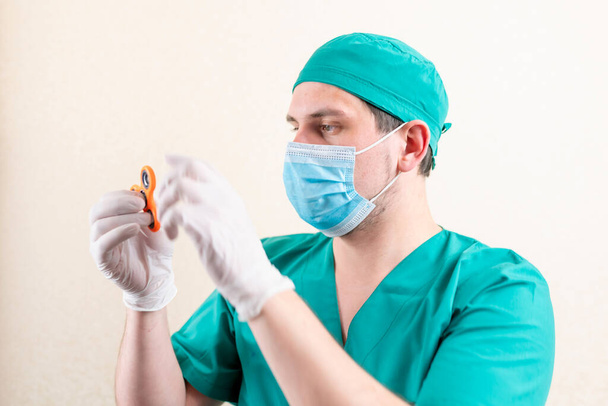 Egy orvos maszkban és kesztyűben, egy fonóval a kezében. Kiváló minőségű fénykép - Fotó, kép