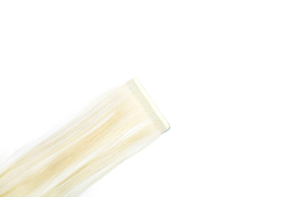 Ψεύτικα ξανθά μαλλιά σε κολλητική ταινία σε λευκό απομονωμένο φόντο - Φωτογραφία, εικόνα