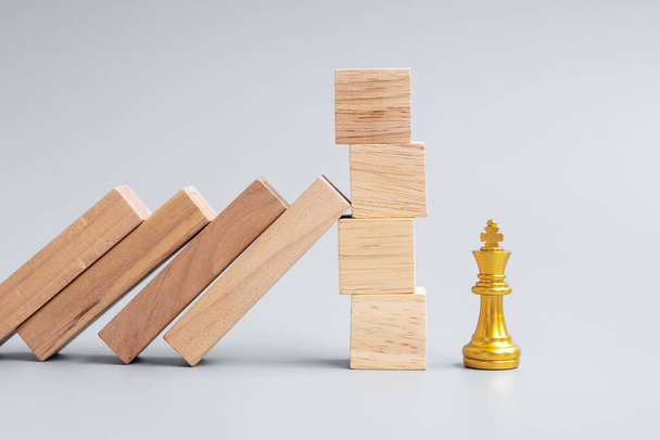 wooden Blocks or Dominoes falling to golden Chess King figure. Business, Risk Management, Solution, economic regression, Insurance - Photo, Image
