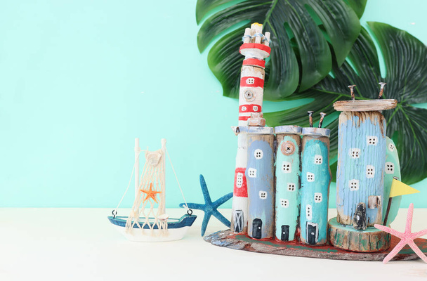 Nautical concept with sea life style objects as boat, driftwood beach houses, seashells and starfish over wooden table and blue background - Fotoğraf, Görsel
