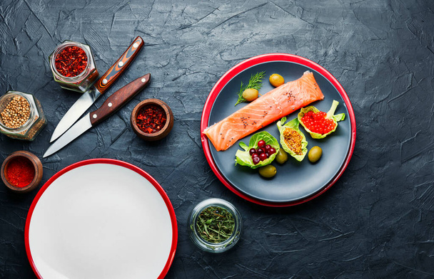 Gesalzener Lachs auf einem Teller mit rotem Kaviar, Oliven und Preiselbeeren. - Foto, Bild