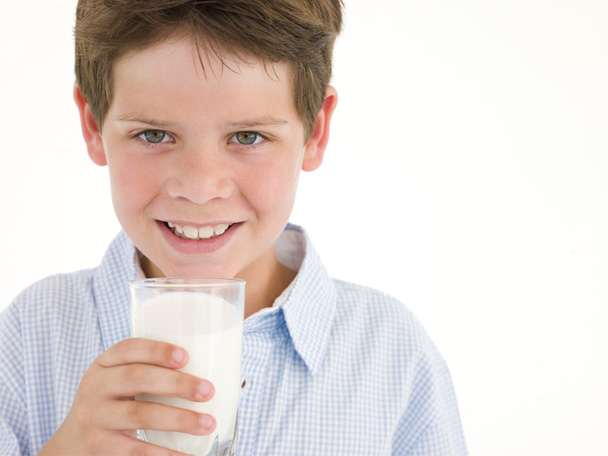 νεαρό αγόρι με το ποτήρι γάλα χαμογελώντας - Φωτογραφία, εικόνα