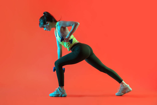 Sporty young woman training with dumbbells on color background - Foto, afbeelding