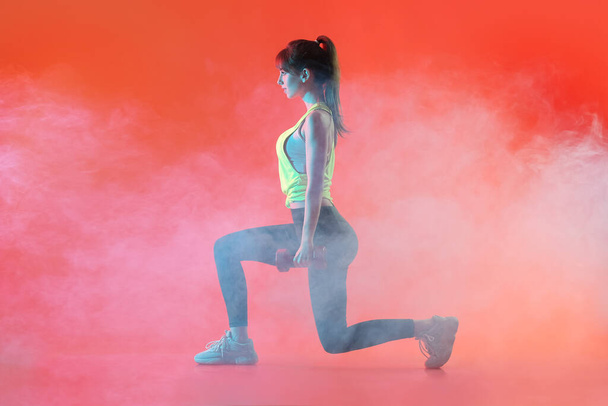 Αθλητική νεαρή γυναίκα εκπαίδευση με αλτήρες στο φόντο χρώμα - Φωτογραφία, εικόνα