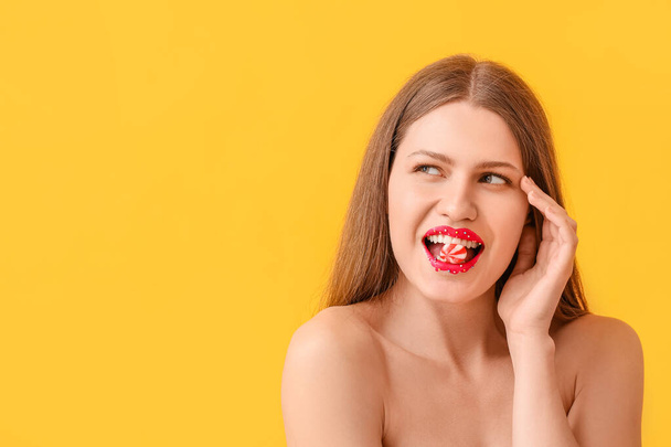 Beautiful young woman with creative makeup and candy on color background - Valokuva, kuva