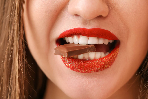 Beautiful young woman with sweet chocolate, closeup - Photo, Image