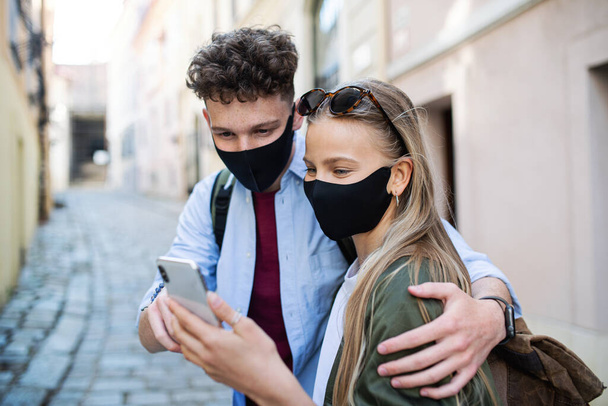 Young couple travelers using smartphone sightseeing in city on holiday, coronavirus concept. - Zdjęcie, obraz