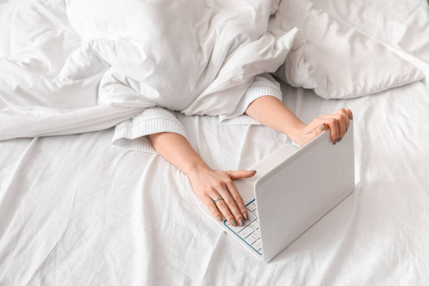 Молодая женщина с ноутбуком в спальне - Фото, изображение