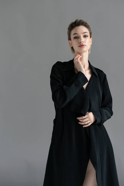 młoda piękna kobieta pozowanie w czarnym płaszczu w studio - Zdjęcie, obraz