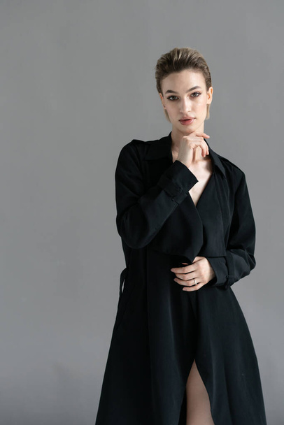 young beautiful woman posing in a black cloak in the studio - Foto, imagen