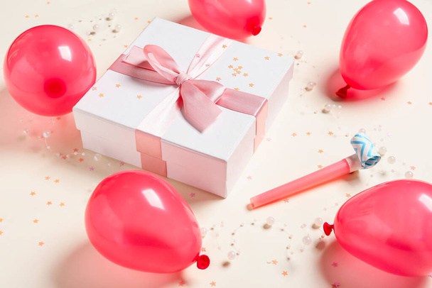 Globos de aire, caja de regalo y confeti sobre fondo de color - Foto, Imagen