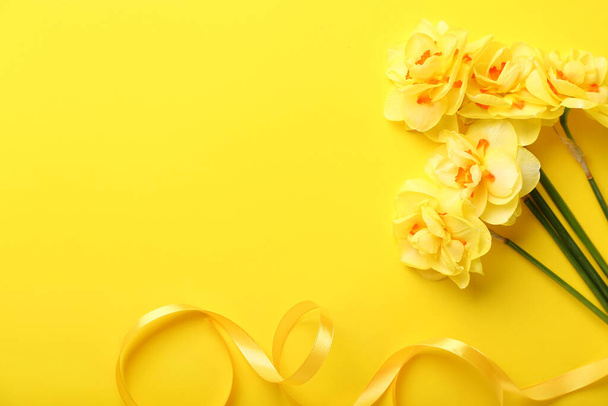 Bouquet of beautiful narcissus flowers and ribbon on color background - Foto, afbeelding