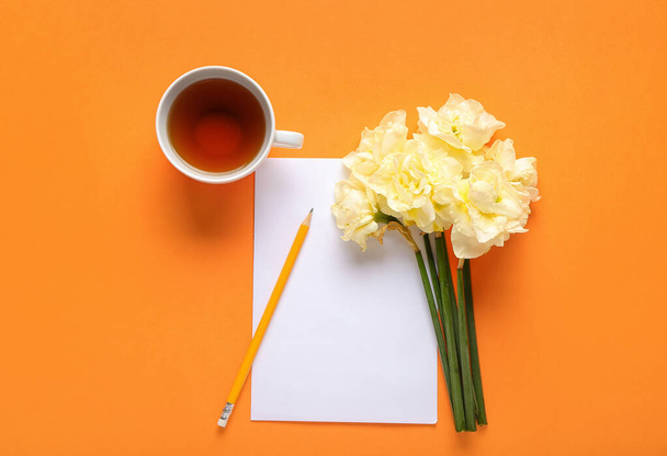 Σύνθεση με όμορφα λουλούδια νάρκισσος και φλιτζάνι τσάι σε φόντο χρώματος - Φωτογραφία, εικόνα