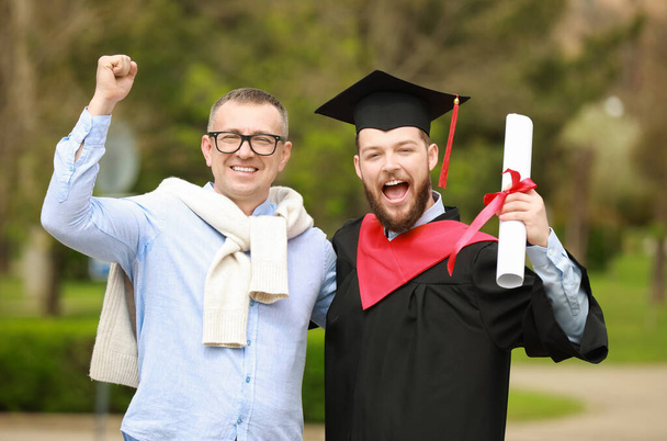 Glücklicher junger Mann mit seinem Vater am Abschlusstag - Foto, Bild