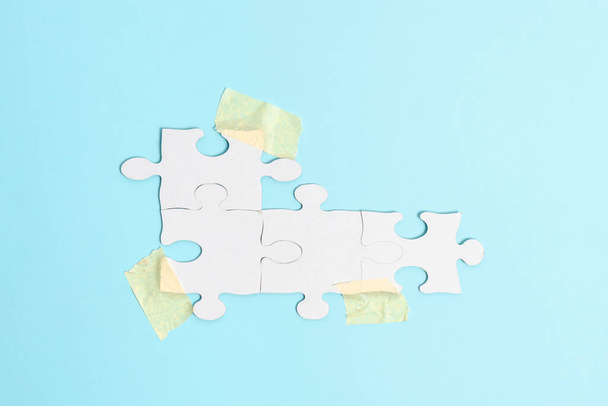 Décryptages White Jigsaw Pattern Puzzle Pieces à connecter avec la dernière pièce manquante positionnée sur un fond plat avec différentes textures et fournitures en papier Accessoires - Photo, image