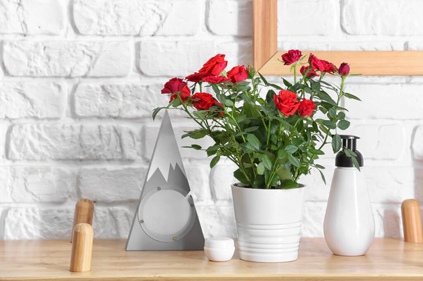Belles roses rouges en pot et décor sur étagère près du mur de briques - Photo, image