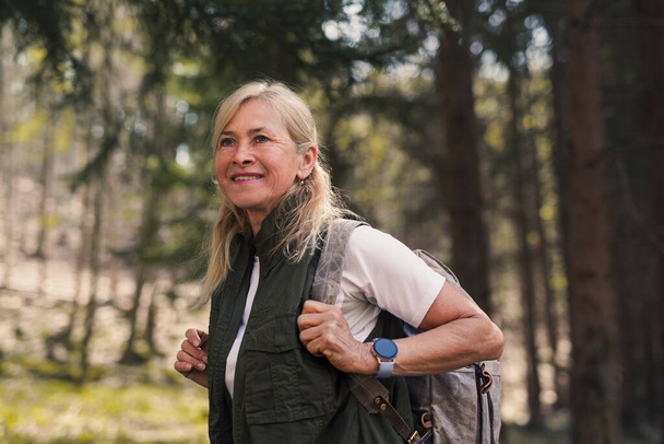 Senior woman hiker outdoors walking in forest in nature, walking. - Foto, imagen
