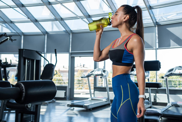 Спортивна жінка п'є воду під час тренувань у спортзалі
 - Фото, зображення