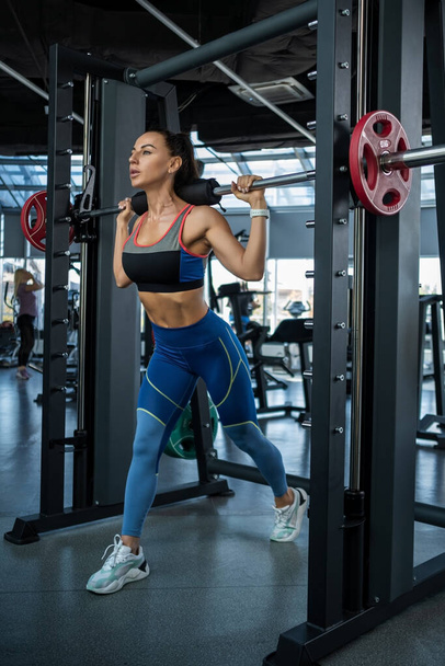 Kobieta robi odwrotne rzuty na maszynie Smitha na siłowni - Zdjęcie, obraz