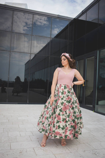 A pretty Caucasian woman with a floral skirt posing in front of a restaurant building - Zdjęcie, obraz
