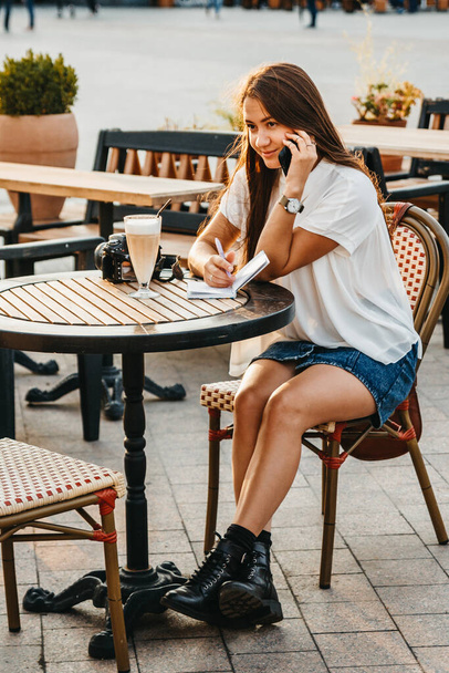Woman is working outdoors at cafe terrace. Freelance worker is t - Фото, зображення