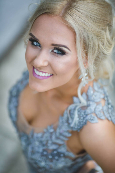 A pretty blonde Caucasian woman with a silver evening dress posing outdoors - Zdjęcie, obraz