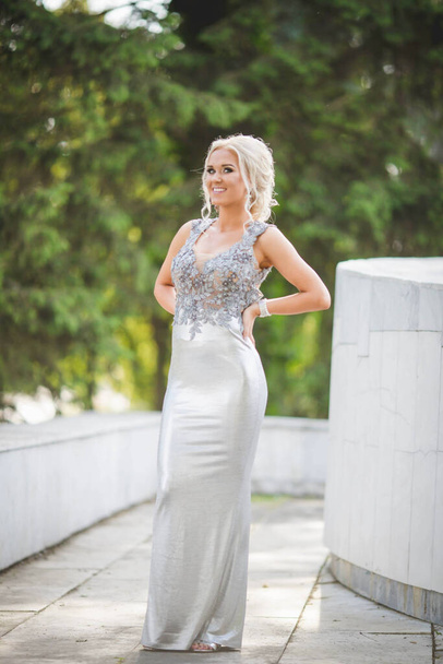 A vertical shot of a smiling caucasian female in a luxury evening dress - Фото, изображение