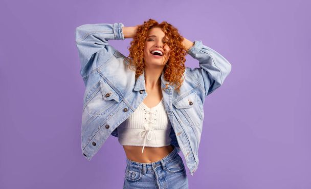 Cute redhead hipster girl with curls in denim jacket isolated on purple background. - Foto, immagini