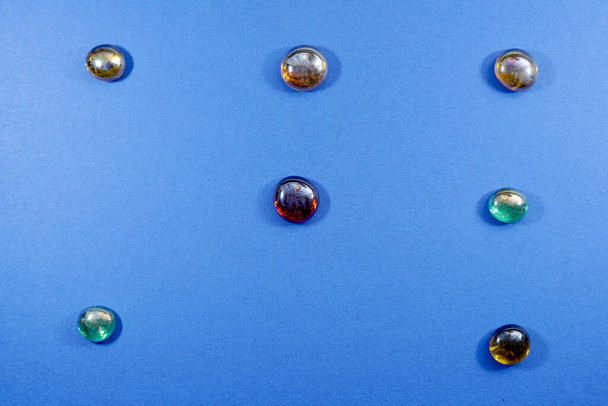 A top view of colorful glass stones on a blue background - Fotó, kép