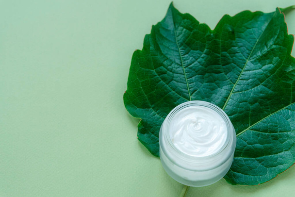 Cosmetic cream jar on green grape leaf. Natural organic handmade cosmetics concept. Top view, flat lay. - Photo, Image