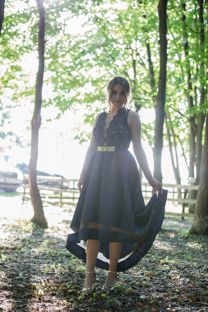 An attractive Caucasian female wearing an elegant dark blue dress posing in a park - Foto, Bild