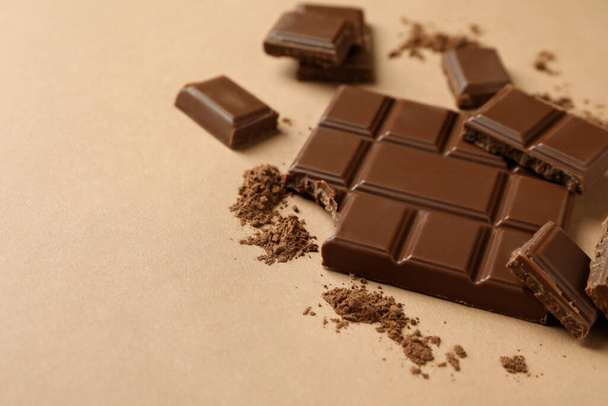 Νόστιμη σοκολάτα και σκόνη σε μπεζ φόντο - Φωτογραφία, εικόνα