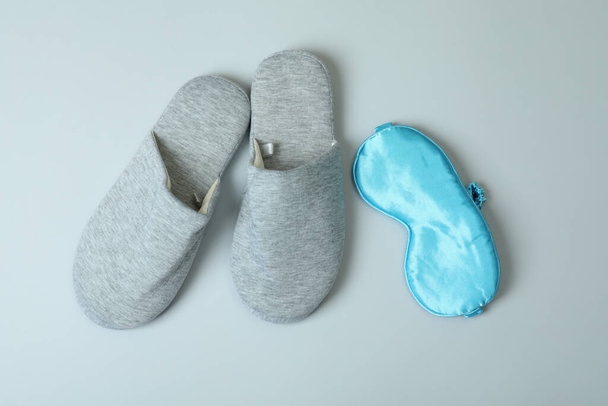 Zapatillas grises y máscara para dormir sobre fondo gris - Foto, imagen