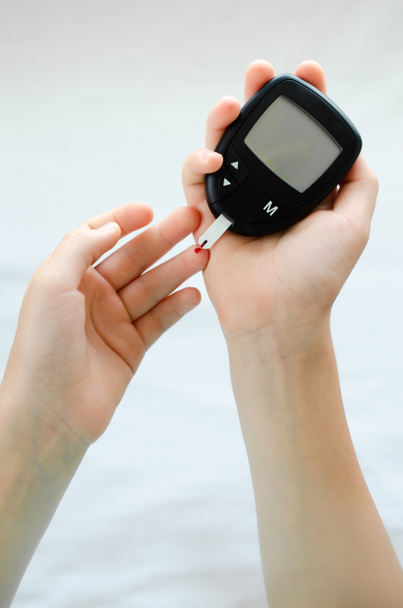 Diabetes concept - vinger van het kind met bloeddruppel tot het controleren van de bloedsuikerspiegel - Foto, afbeelding