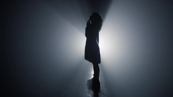 Silhouette imádkozó lány a házban. Nő személy összecsukható kezét imádság a sötétben. - Felvétel, videó
