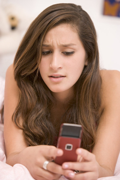 Teenage Girl Lying On Her Bed Using Mobile Phone - Фото, изображение