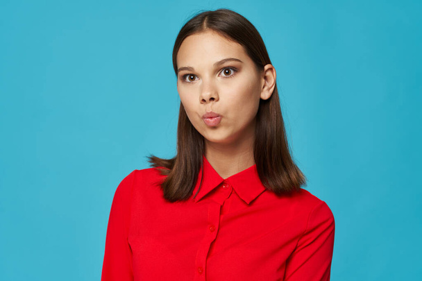 pretty woman in red shirt emotions grimace Studio blue background - Photo, Image
