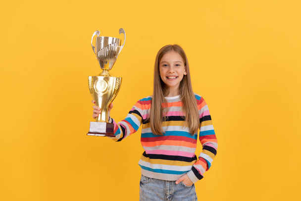 Счастливый ребенок держит золотую чашу. Премия за достижения. Празднование успеха школы. - Фото, изображение