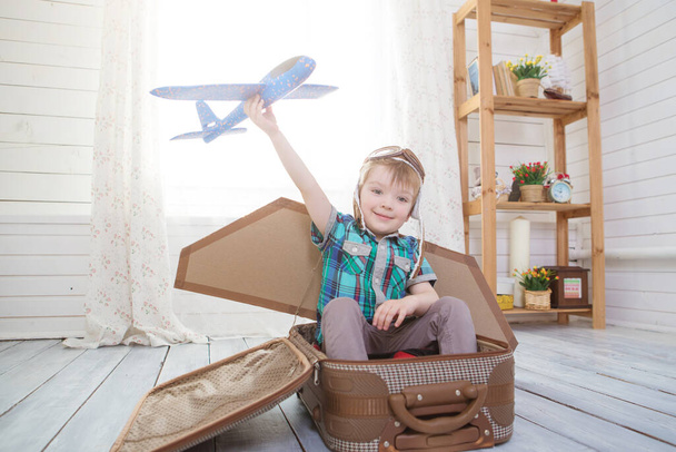 Children boy wearing pilot costume making ready to fly gesture standing on living room wooden floor at home - Foto, afbeelding