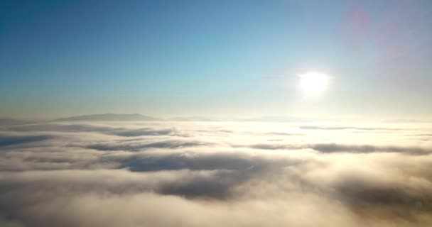 Luftaufnahme eines majestätischen Sonnenaufgangs in den Bergen. Tal zwischen den Bergen ist mit Nebel bedeckt und wird von den warmen Strahlen der aufgehenden Sonne beleuchtet. Berge mit natürlichem Wald bedeckt. - Filmmaterial, Video