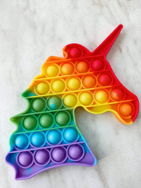 Pásalo. Juguete arco iris para niños en forma de cabeza de unicornio - Foto, imagen