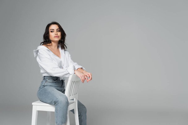 Young woman in jeans and white shirt looking away isolated on grey  - Foto, imagen