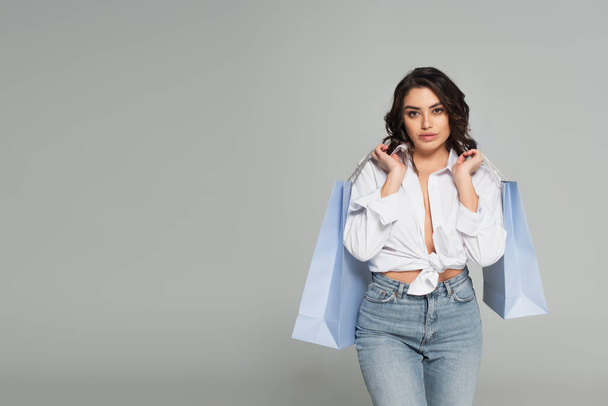 Sexy woman in white shirt holding purchases isolated on grey - Photo, Image