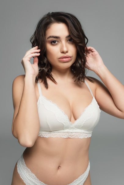 Pretty brunette woman in lingerie looking at camera isolated on grey - Photo, Image