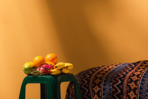 exotic fruits on stool near ornament blanket on orange - Φωτογραφία, εικόνα