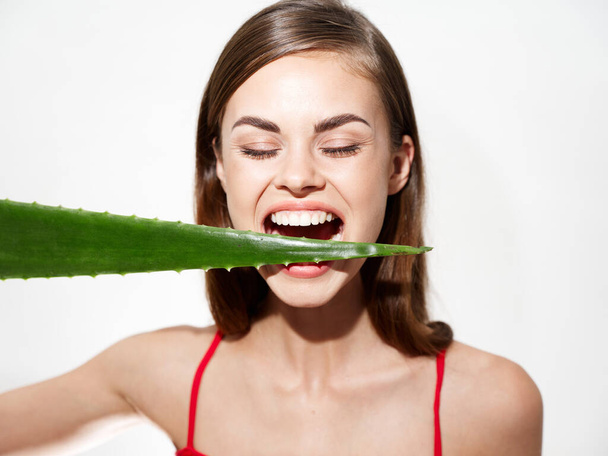 Green aloe leaf in the teeth of an energetic woman with closed eyes - Fotó, kép